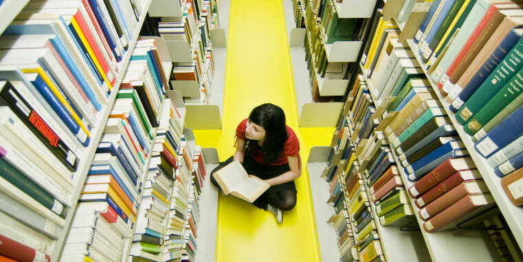 Foto Person in Bibliothek auf Boden sitzend