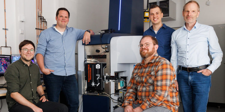 The research team from the Institute of Hygiene at the University of Münster with the modified fluorescence microscopy–t-MALDI-2 mass spectrometer. From left to right: Dr Sebastian Beßler, Dr Alexander Potthoff, Dr Jens Soltwisch, Dr Jan Schwenzfeier, Prof Dr Klaus Dreisewerd.<address>© Peter Leßmann</address>