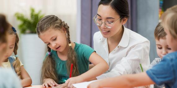 Young-teacher-helping-her-students-class 2 Zu 1