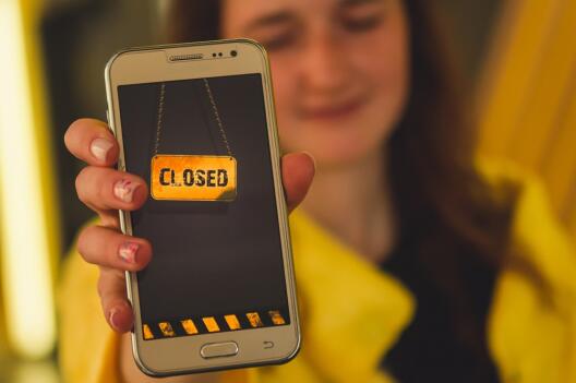Junge Frau hält Smartphone - Screen mit der Aufschrift "Closed"