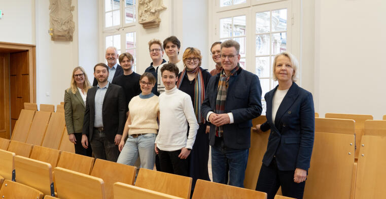 Zwölt Personen stehen in einem Hörsaal.