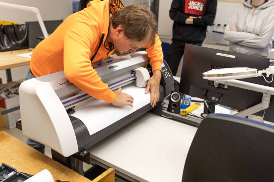 Thomas Wächter zeigt den Azubis die Arbeit mit dem Plotter, einer digitalen Schneidemaschine.<address>© Uni MS - Linus Peikenkamp</address>