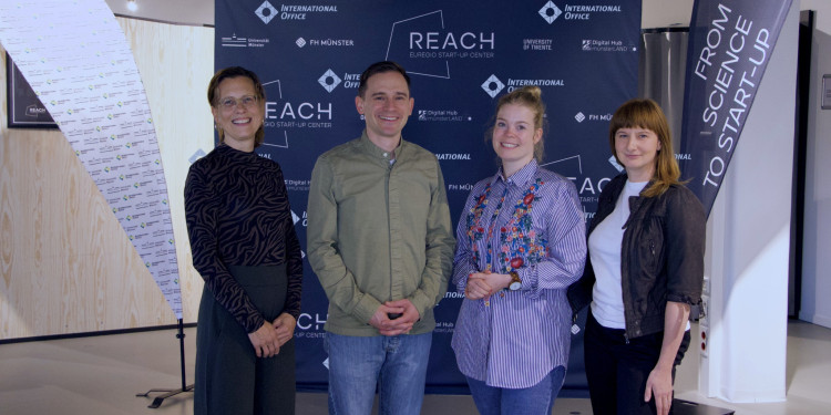 Four people stand in front of a banner with the REACH – EUREGIO Start-up Center logo. The photo shows (from left) Maria Homeyer, Dr. Christian Wiencierz, Dr. Natalie Powroznik and Katy Krukar.<address>© Uni MS</address>