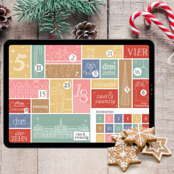 Tablet, auf dem der Adventskalender zu sehen ist, vor einem weihnachtlichen Hintergrund.<address>© Uni Münster</address>