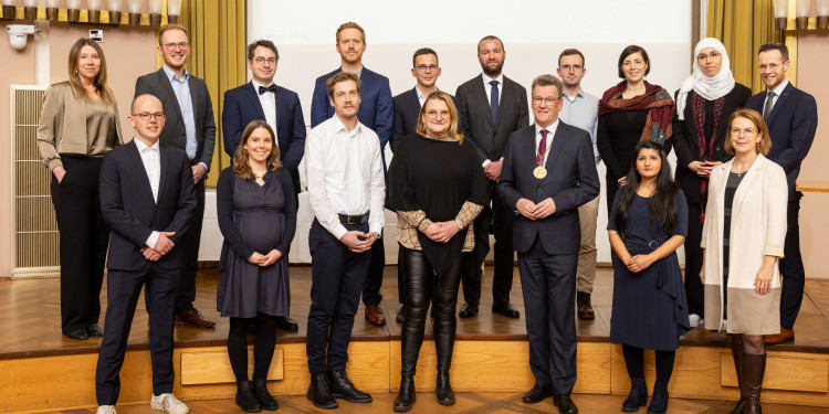 Ein Gruppenfoto zeigt 17 Personen, die auf der Bühne der Aula stehen.<address>© Uni MS - Peter Leßmann</address>