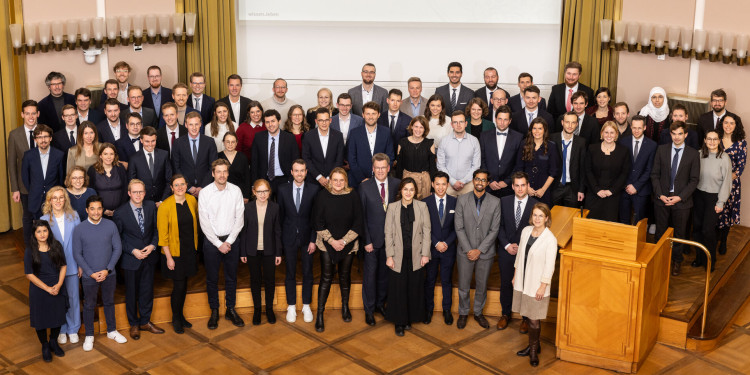 Ein Gruppenfoto zeigt über 100 Personen, die auf der Bühne der Aula stehen.<address>© Uni MS - Peter Leßmann</address>