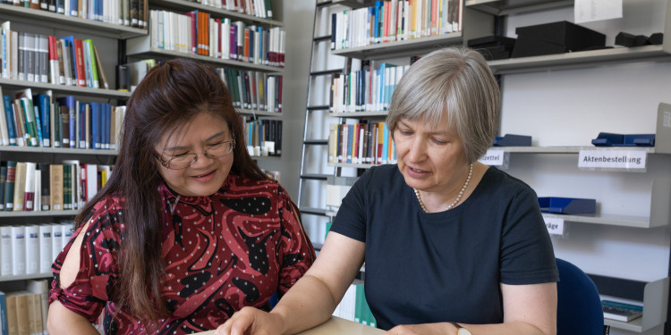 Together with Dr. Sabine Happ (right), Dong-Nan Zhu browses through her grandmother’s certificates.<address>© Uni MS - Linus Peikenkamp</address>