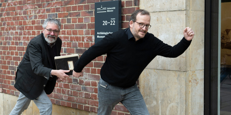 Dr Helge Nieswandt (left) symbolically hands over the museum’s inventory book to his successor, Dr Torben Schreiber.<address>© Uni MS - Brigitte Heeke</address>