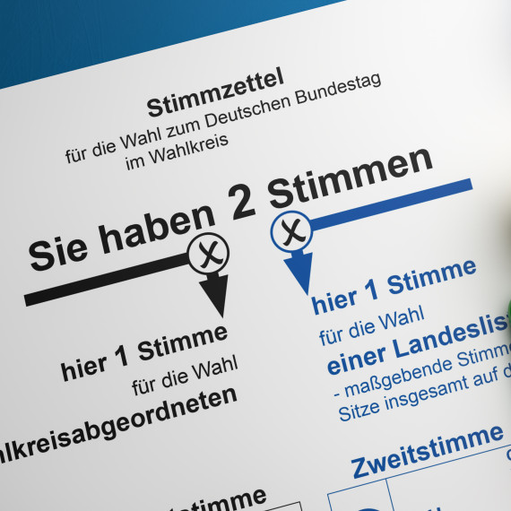 Links auf dem Bild ist ein Wahlschein zu sehen, auf denen man Kreuze für die Erst- und die Zweitstimme setzen kann. Rechts auf dem Bild befinden sich Buttons mit den Logos verschiedener deutscher Parteien.<address>© Andreas Prott - stock.adobe.com</address>