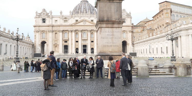 Die rund 20-köpfige Delegation steht während eines Gesprächs vor einem Obelisken. Im Hintergrund ist der Petersdom zu sehen.<address>© Uni MS - Johannes Wulf</address>